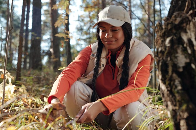 Niña afroamericana con gorra cortando boletus antes de ponerlo en la canasta