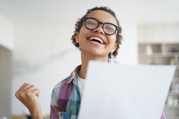 Una niña afroamericana llena de alegría tiene una carta de la universidad Logro de objetivos y concepto de victoria