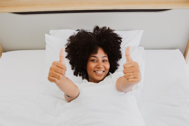 Niña afroamericana sana y alegre en la cama durmiendo profundamente despertándose refrescada.