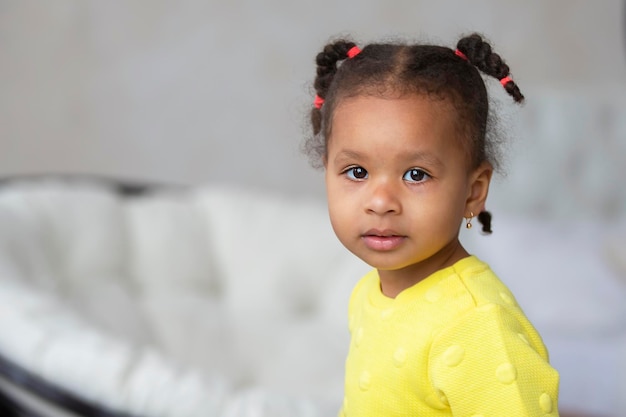 Niña afroamericana con un vestido amarillo mira a la cámara