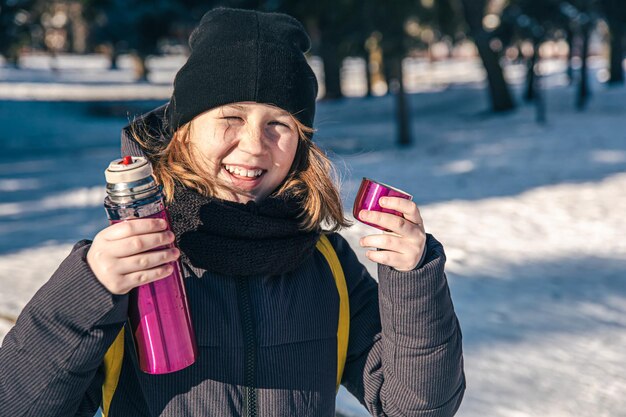 Una niña afuera con termo en un frío día de invierno.