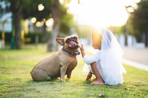 Foto niña agachada por el perro en la hierba