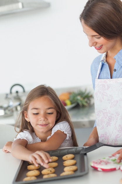 Niña agarrando una galleta de una bandeja para hornear