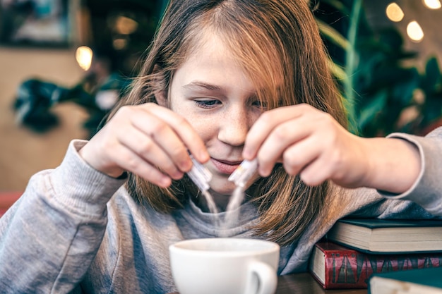 Una niña agrega azúcar a su té.