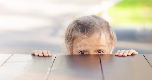 la niña ahora se asoma desde detrás de la superficie de la mesa