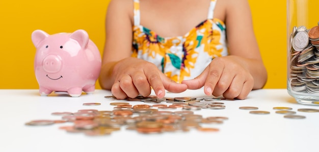 Niña ahorrando dinero Imagen de una niña contando dinero para ahorrar en un vaso