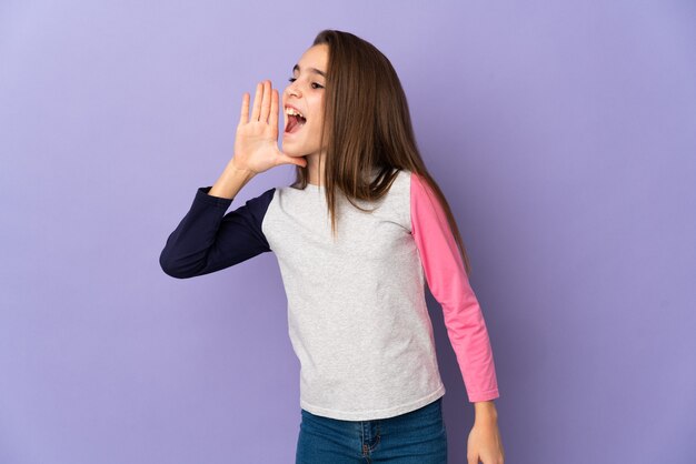 Foto niña aislada en la pared púrpura gritando con la boca abierta hacia el lado