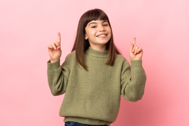 Niña aislada en la pared rosa apuntando hacia una gran idea