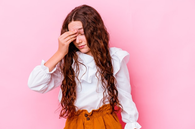 Niña aislada en la pared rosa con dolor de cabeza, tocando el frente de la cara