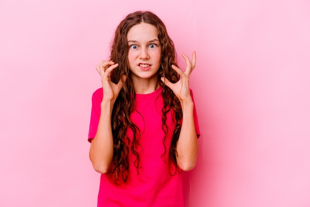 Niña aislada en la pared rosa molesta gritando con las manos tensas