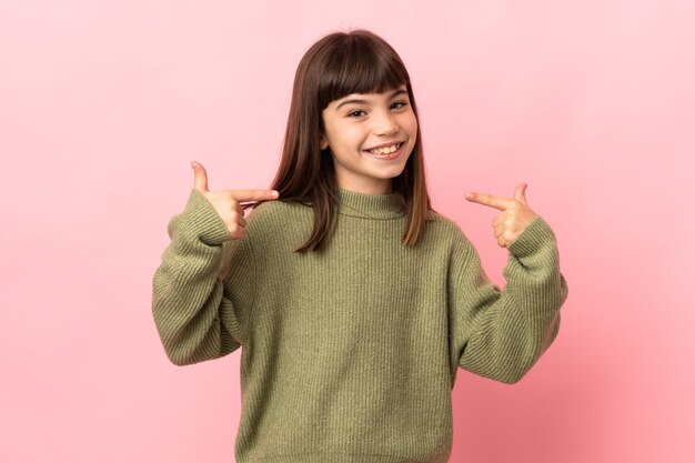 Niña aislada en la pared rosada dando un pulgar hacia arriba gesto