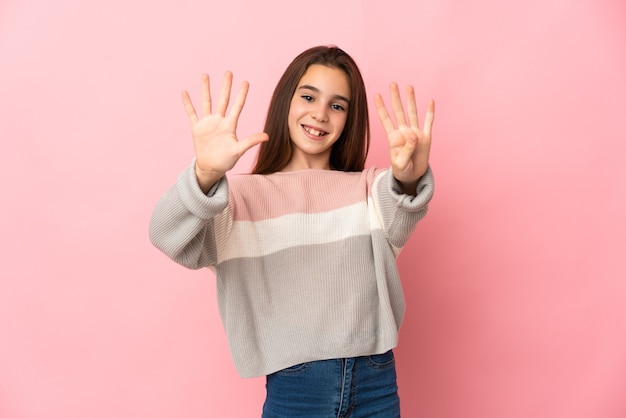 Niña aislada sobre fondo rosa contando nueve con los dedos