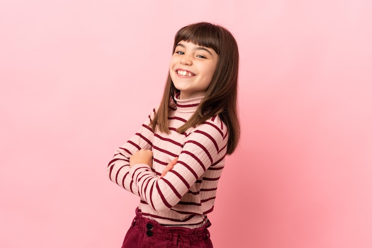 Foto niña aislada sobre fondo rosa feliz y sonriente