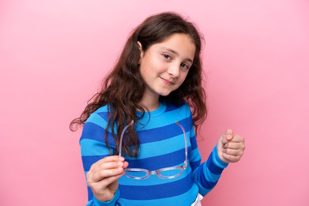 Niña aislada sobre fondo rosa Con gafas con expresión feliz