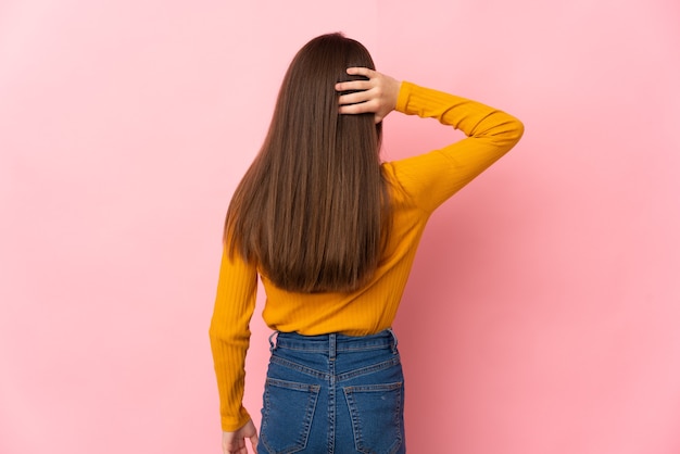 Niña aislada sobre fondo rosa en posición trasera y pensando