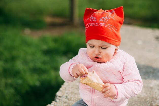 Niña al aire libre en el pueblo comiendo helado con mucha avidez