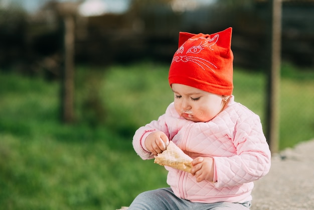 Niña al aire libre en el pueblo comiendo helado con mucha avidez