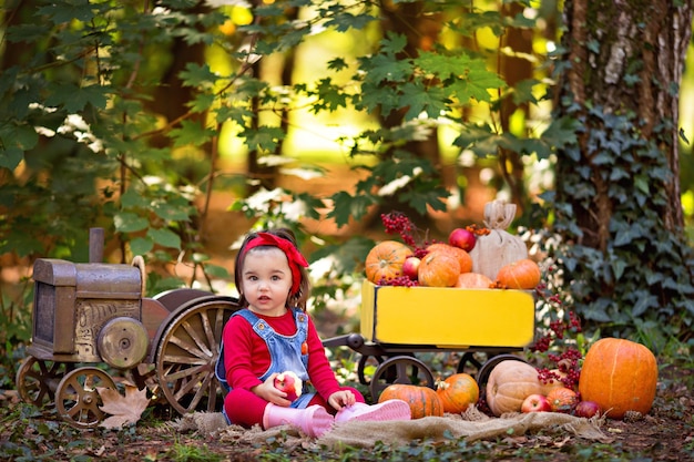 niña al lado del tractor con un carro con calabazas