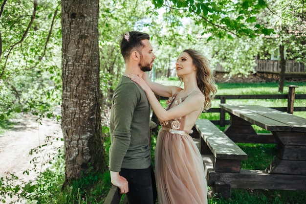 La niña alcanza el beso. El concepto de una historia de amor. Alrededor de la hierba verde y los árboles en flor.