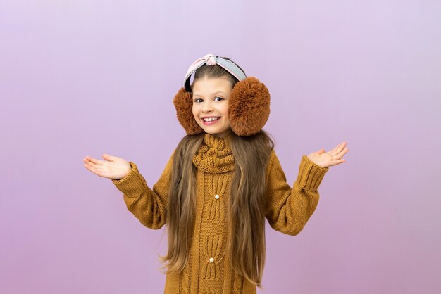Una niña alegre con auriculares cálidos mira a la cámara un niño con un suéter cálido en un fondo aislado