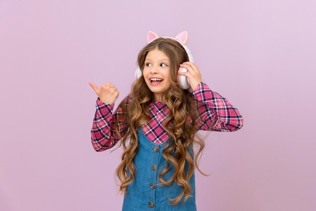 Una niña alegre con auriculares nuevos escucha música