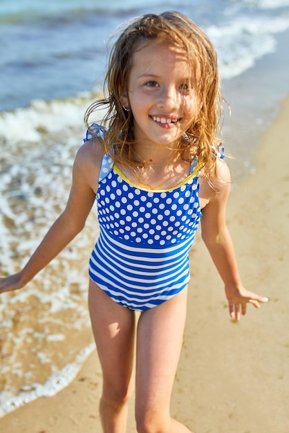 Niña alegre feliz correr en la playa