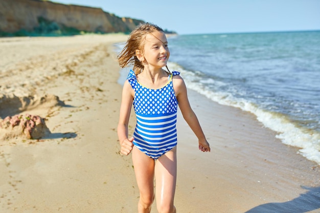 Niña alegre feliz correr en la playa