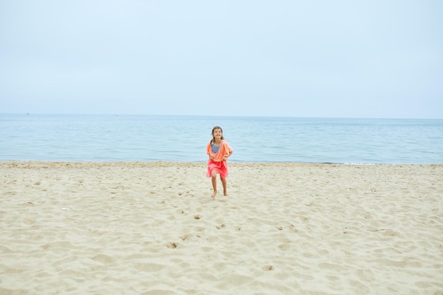 Niña alegre feliz correr en la playa