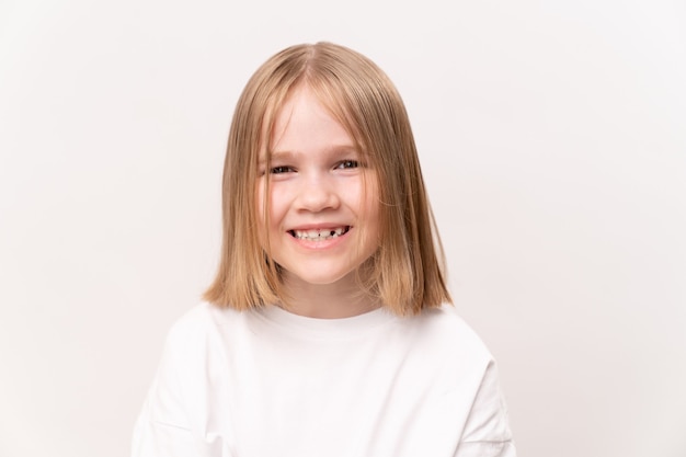 Niña alegre y feliz con un corte de pelo quad sobre un fondo blanco. infancia feliz. vitaminas y medicinas para el niño.