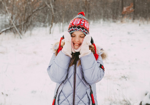 Niña alegre feliz divirtiéndose en el bosque en un día de invierno. niño juega con nieve.