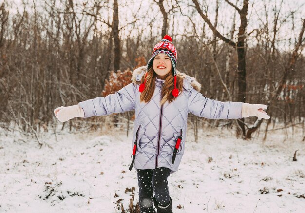 Niña alegre feliz divirtiéndose en el bosque en un día de invierno. niño juega con nieve.