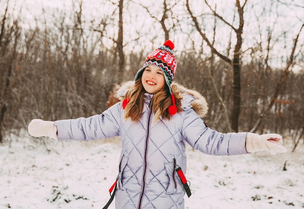 Niña alegre feliz divirtiéndose en el bosque en un día de invierno. niño juega con nieve.