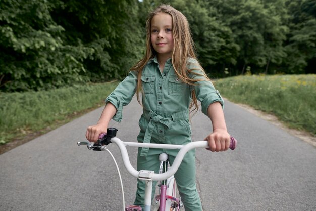 Niña alegre feliz montando en bicicleta en el parque en la naturalezaxD