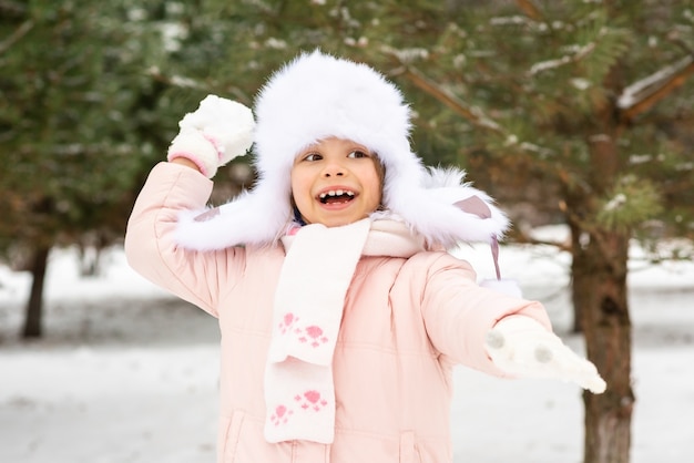 Niña alegre jugando en la nieve.