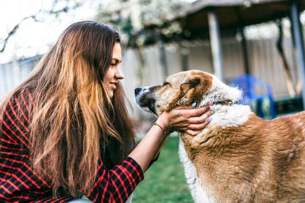 Niña alegre jugando con su perro en el patio de la casa en primavera