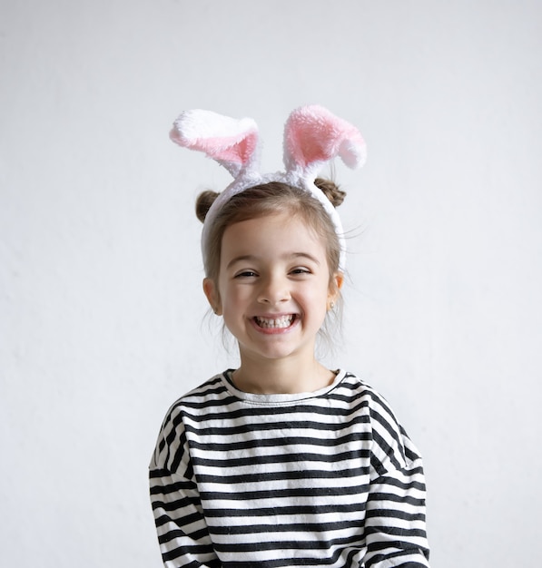 Niña alegre con orejas de conejo de Pascua decorativas en la cabeza.