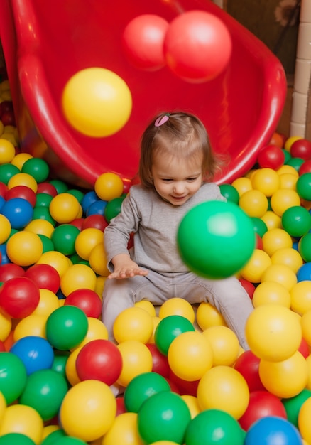 Niña alegre en la piscina con bolas de colores. Centro de entretenimiento para niños