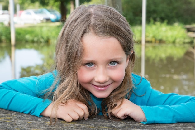 Niña alegre sentada y sonriendo con Green River en segundo plano.