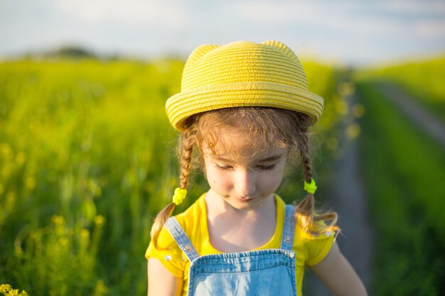 Una niña alegre con un sombrero amarillo en un campo de verano Día del niño alegría vacaciones de clima soleado Un remedio para mosquitos e insectos Estilo de vida cara amable retrato de primer plano