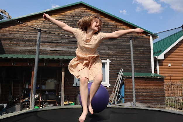 Niña alegre con una sonrisa en la cara con un hermoso vestido saltando en el trampolín