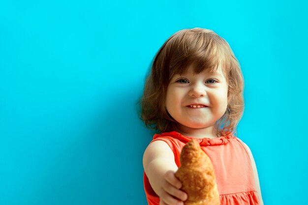 Una niña alegre sosteniendo un croissant en su mano