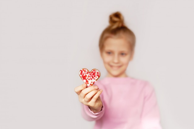 Una niña alegre sostiene pan de jengibre en forma de corazones