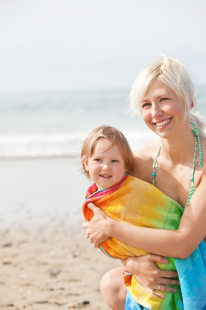 Una niña alegre y su madre sonriente en la playa