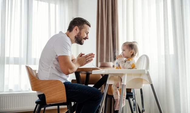Una niña con alergias está sentada en su silla e inhalándose mientras el padre aplaude
