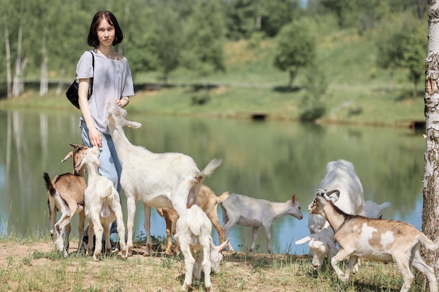 Niña se alimenta y juega con cabras en una granja