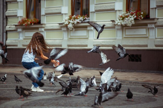 Una niña alimenta palomas en una calle de kiev.