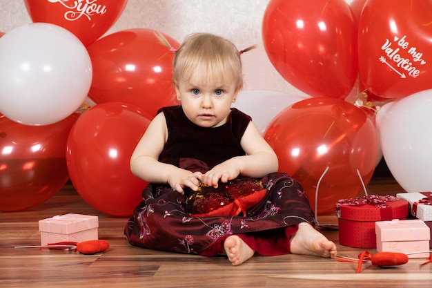 Una niña de un año juega con una almohada de corazón el Día de San Valentín