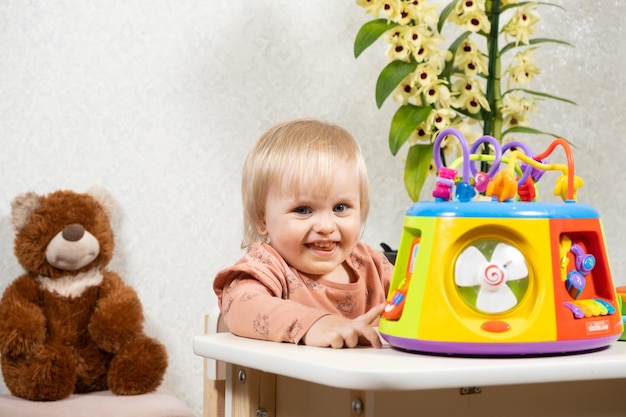 Una niña de un año y medio juega con un juguete musical brillante presiona botones Juguetes para el desarrollo infantil para bebés