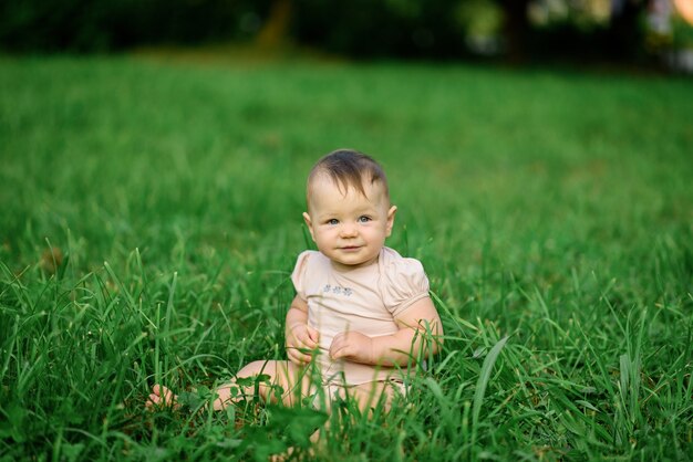 La niña de un año se sienta en la hierba.