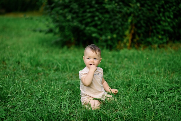 La niña de un año se sienta en la hierba.